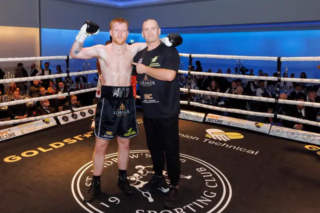 Matthew, a glove raised, beside his cornerman in the ring