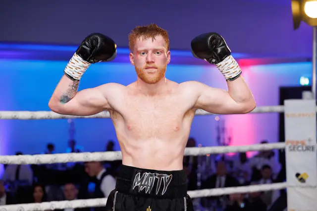 Matthew flexing both arms in the ring